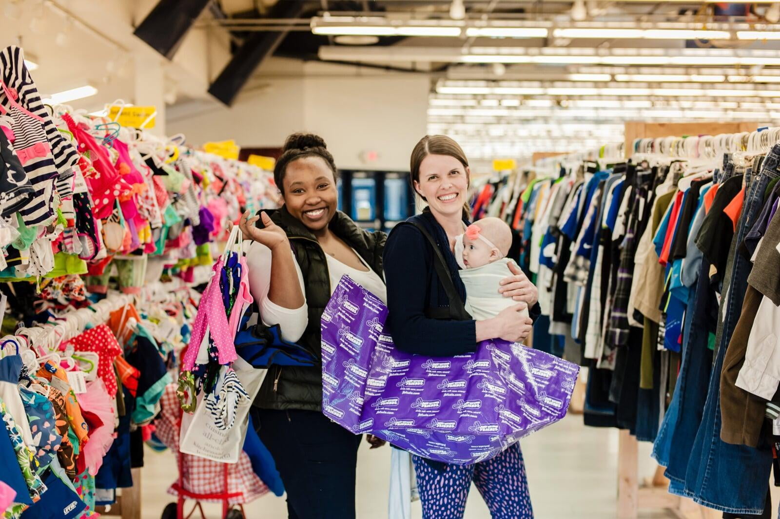 Two friends shop together—one mom wears her baby girl—as they find great deals at their local JBF sale.